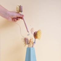 Set of dishwashing brushes with a holder on a light yellow background
